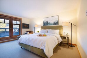 A bedroom with a large bed, two bedside tables, a window with a view, and a painting on the wall. - Charming 4BR/5BA on Golf Course w/ Private Garage (Whistler)