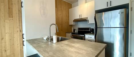 Una cocina moderna con una isla central, electrodomésticos de acero inoxidable e iluminación colgante.