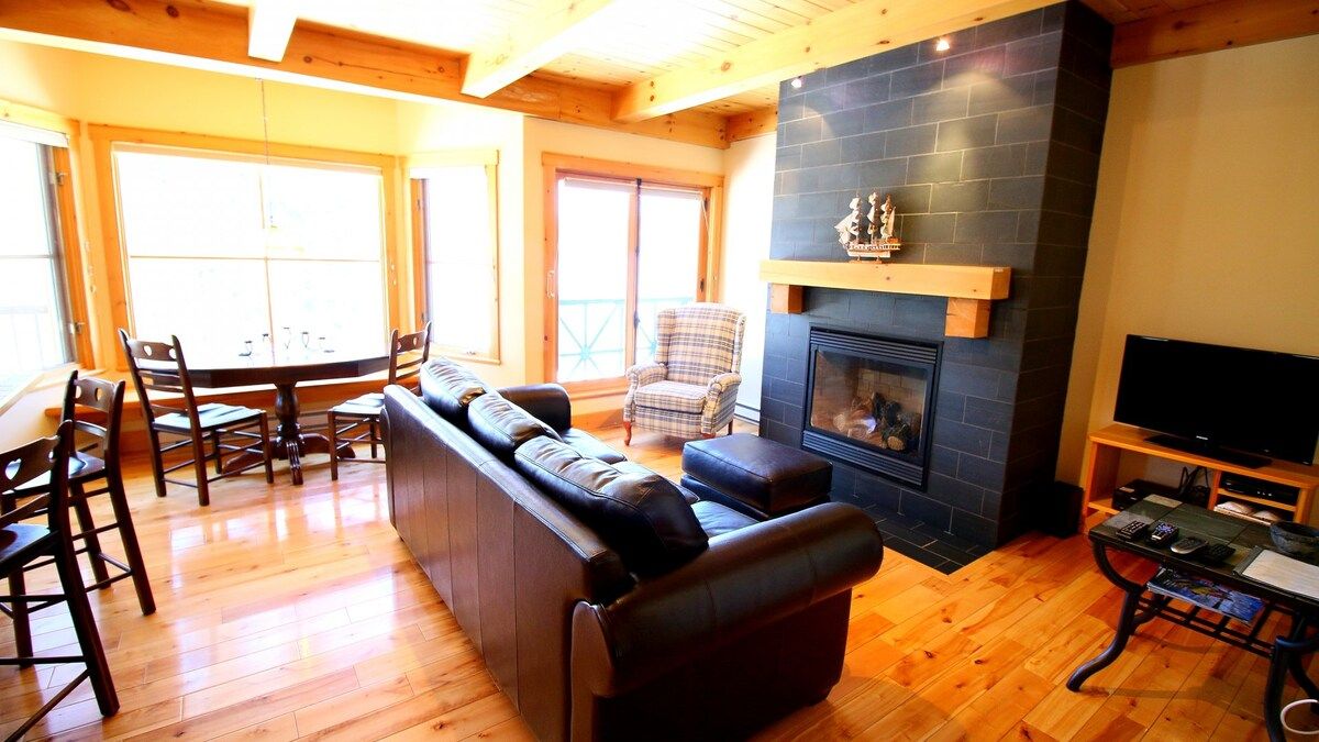 Una sala de estar con chimenea, un sofá, un televisor y un comedor con sillas y una mesa.