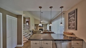 A kitchen with a central island, pendant lights, a coffee bar, and a staircase leading to another level. - Hideaway Retreat at Pocono Summit Lake - Dock, Boats, Hot Tub & Sauna (Pocono Summit)