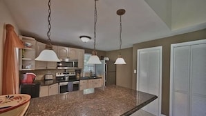 A kitchen with granite countertops, stainless steel appliances, pendant lighting, and white cabinets. - Hideaway Retreat at Pocono Summit Lake - Dock, Boats, Hot Tub & Sauna (Pocono Summit)