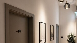 A hallway with a wooden floor, framed pictures on the wall, and a door with a sign. - Berlin Sleep Club (Berlin)