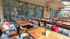 Ein Restaurant mit Terrassensitzgelegenheiten, großen Fenstern und Blick auf die Straße.