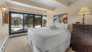 A bedroom with a large bed, a dresser, a painting, and a view through a sliding glass door. - Lld308-2 (Dillon)