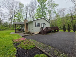 A single-story house with a porch, a chimney, and a driveway leading to a gated entrance. - Highwater Hideaway (Bruceton Mills)