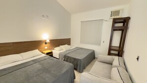 A hotel room with two beds, a desk, a chair, a ladder, and a window.