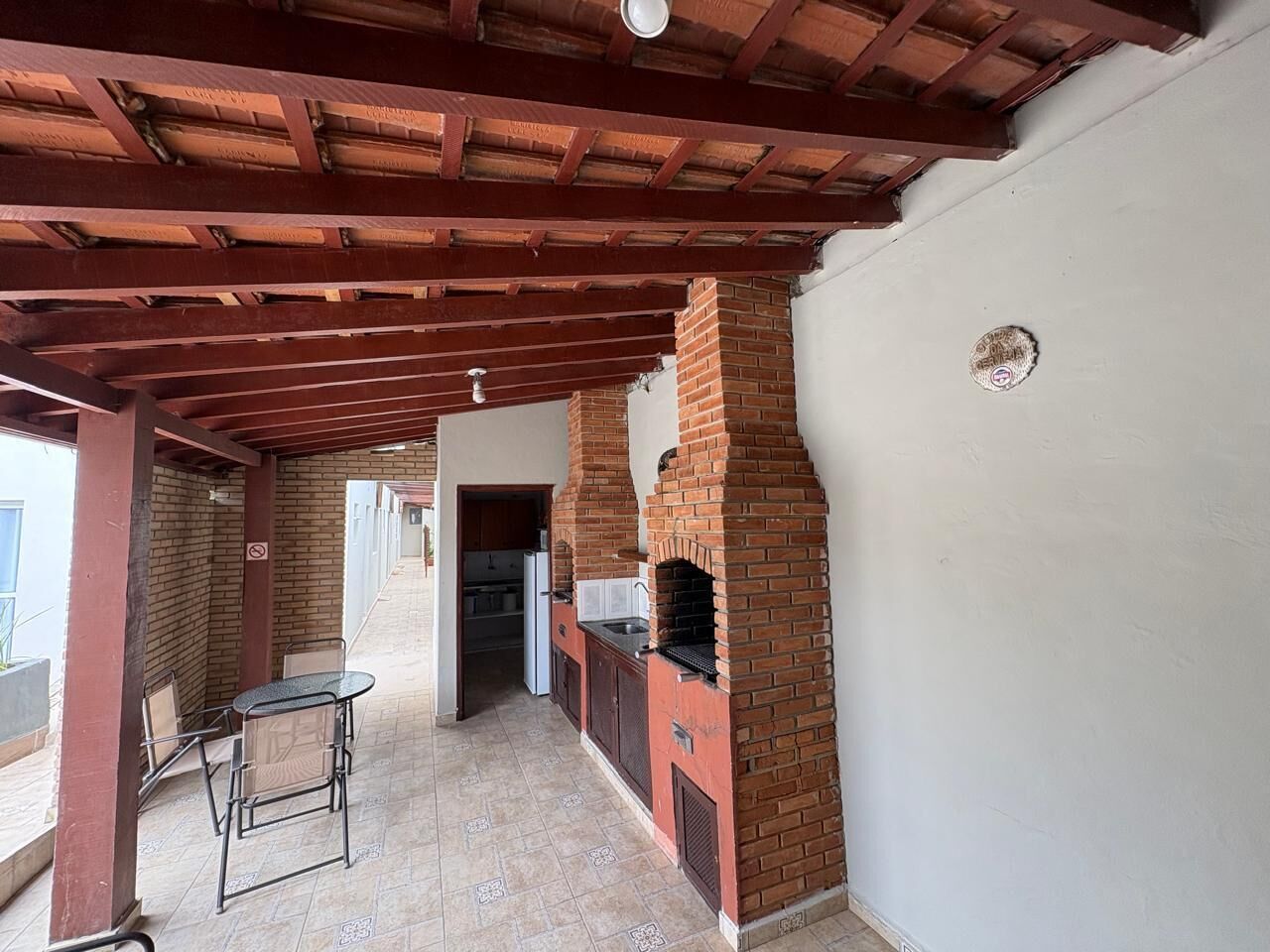 Un patio al aire libre con un horno de ladrillo, una mesa con sillas y una zona de cocina.
