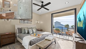 A modern bedroom with a bed, bedside table, and a balcony with a view. - Gulf views, Saltwater lagoon & waterfall, Beach@2min walk, Firepit, Golf Cart, Elevator (Destin)