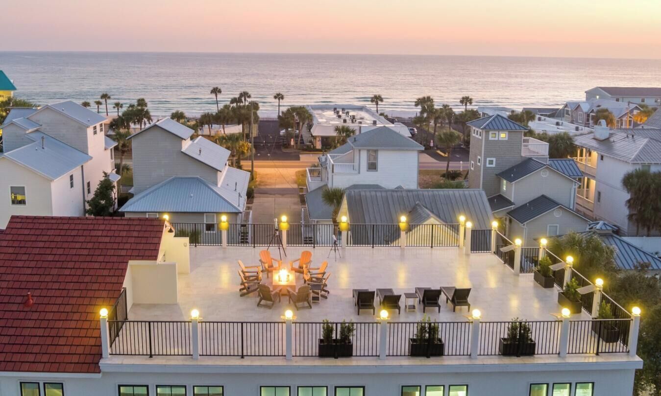 Una zona residencial costera con casas, un patio con mobiliario exterior y vista al océano.