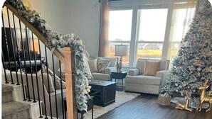 A spacious living area with a wooden staircase, a Christmas tree, and a cozy seating arrangement. - New house. 20 minutes from ATX, 5 bedrooms (Manor)