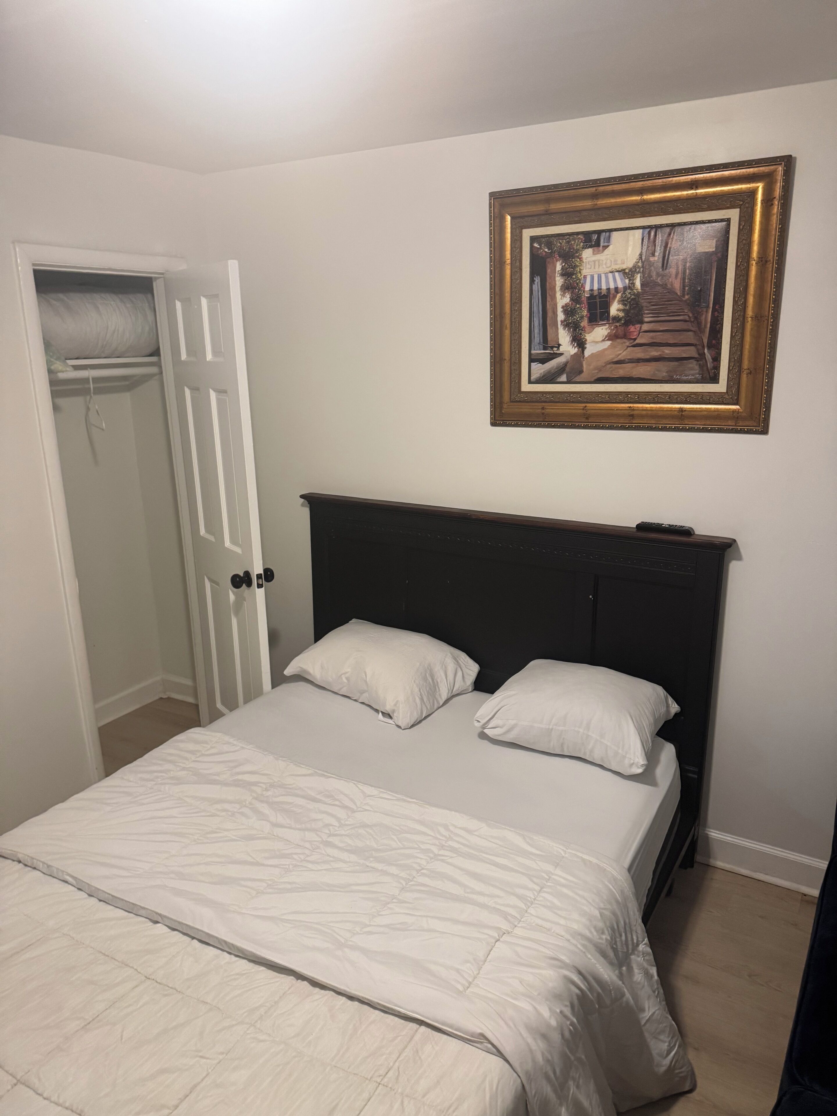 Un dormitorio con una cama, una puerta y un cuadro en la pared.