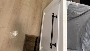 Ein Schlafzimmer mit Holzboden, einem Bett mit weißem Kopfteil und einem weißen Kleiderschrank mit mehreren Schubladen.