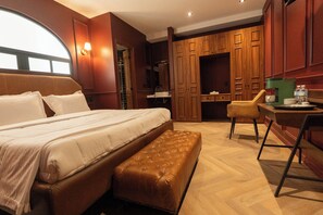 A hotel room with a large bed, a bench, a desk, and wooden cabinets. - The Urban Muse suite (Mexico City)