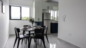 Een moderne keuken met witte kasten, een roestvrijstalen koelkast, en een eethoek met een ronde tafel en vier stoelen.