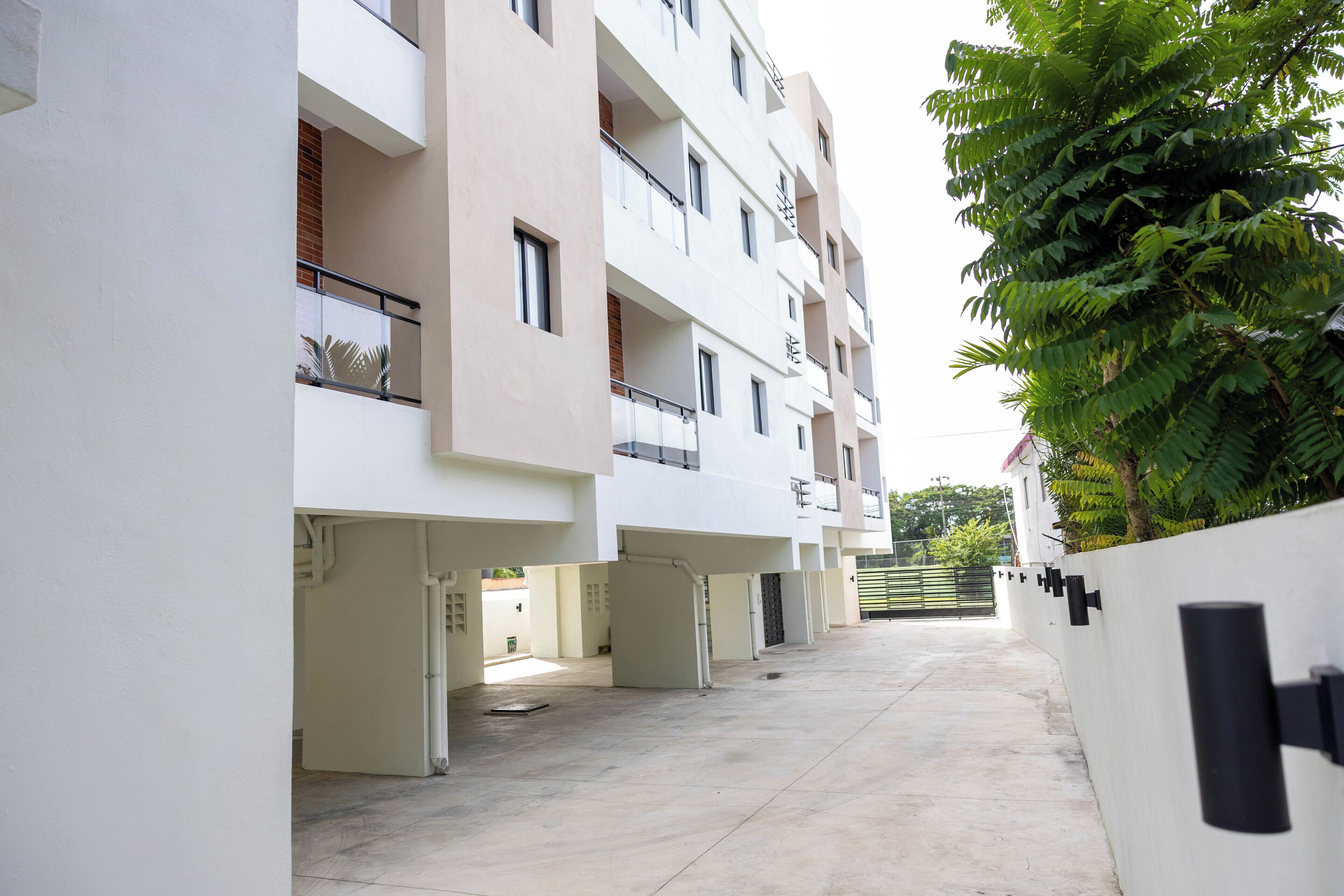 Un immeuble résidentiel à plusieurs étages, doté de balcons, d’une cour pavée et d’un mur végétal.