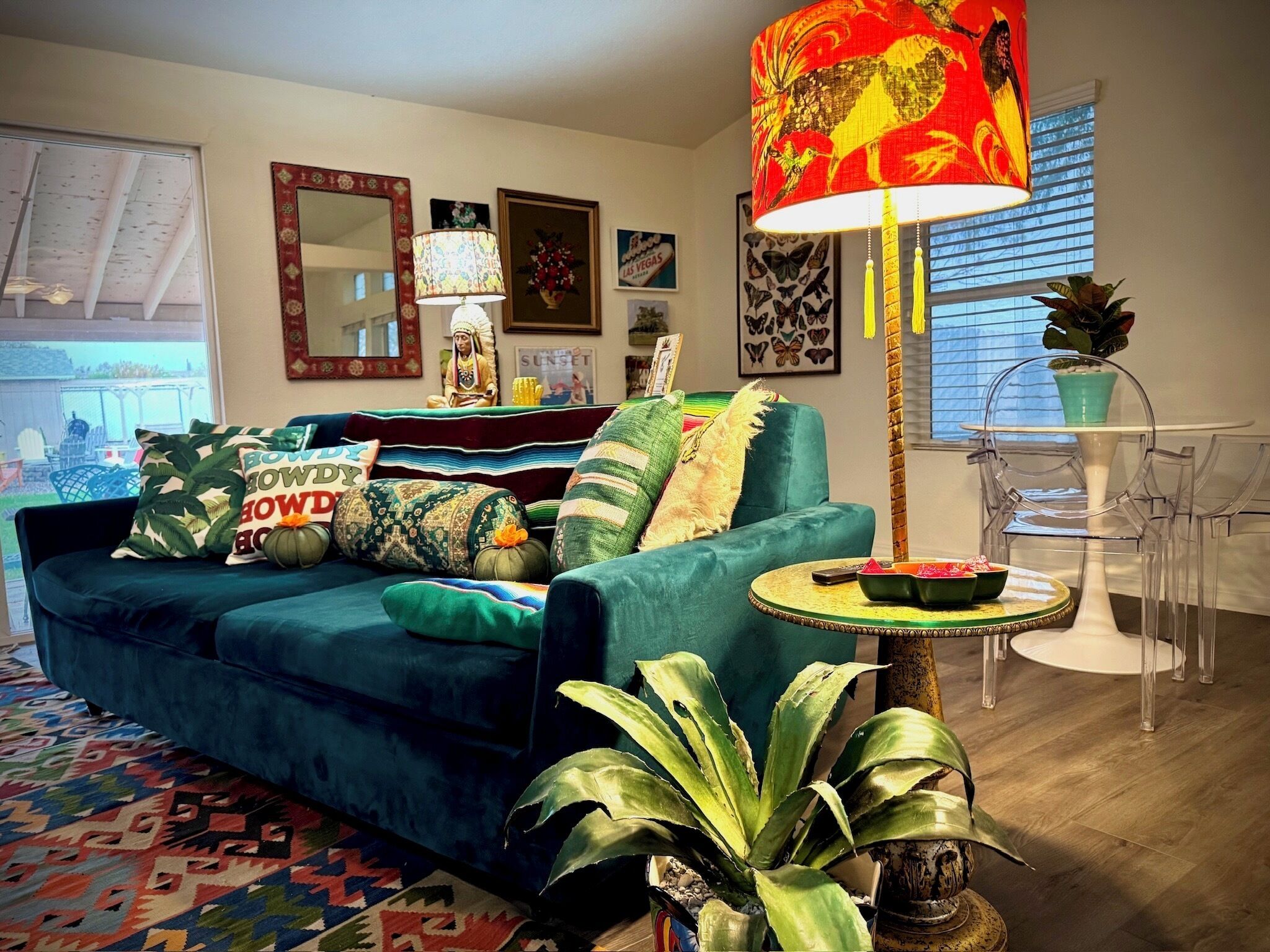 A living room with a teal sofa, patterned cushions, a round table, and a tall floor lamp.