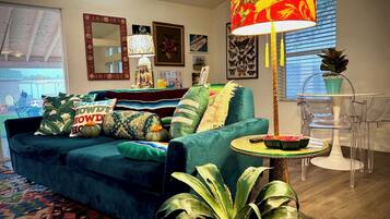 A living room with a teal sofa, patterned cushions, a round table, and a tall floor lamp.