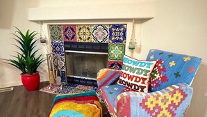 Una sala acogedora con chimenea, cojines coloridos, una cesta tejida y una planta en maceta.