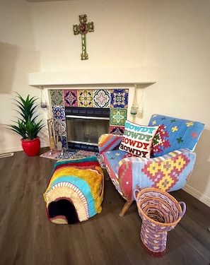Una sala acogedora con chimenea, cojines coloridos, una cesta tejida y una planta en maceta.