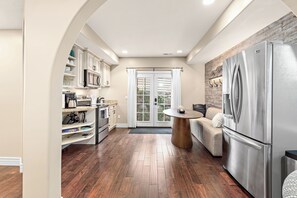 A kitchen with a stainless steel refrigerator, wooden flooring, and a dining area with a round table. - Snuggle Down Inn: 1BR In-Law Basement Suite (Heber City)