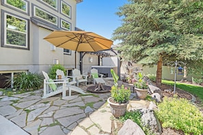 A patio with stone flooring, outdoor furniture, and potted plants. - Snuggle Down Inn: 1BR In-Law Basement Suite (Heber City)