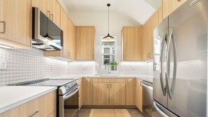 Een moderne keuken met houten kastjes, een roestvrijstalen koelkast en een witte betegelde achterwand.