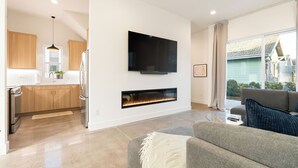 Een moderne woonkamer met een open haard, een flatscreen televisie aan de muur en een bank.