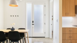 Een moderne keuken met houten kastjes, een witte betegelde spatwand en een dubbele deur met geëtste glaspanelen.