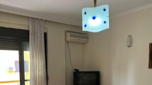 Et spiseområde med et bord, stole, et fjernsyn og en loftlampe.