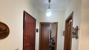 En gang med ventilator, lampe og en dør, der fører til et andet rum.