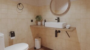 Ein Badezimmer mit Waschbecken, Spiegel, Toilette und Mülleimer.