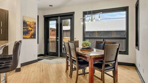 Ein Essbereich mit Holztisch und -stühlen, einem Bild an der Wand und Blick durch ein Fenster.