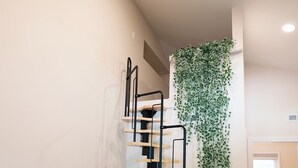 Een modern interieur met een trap, een groene bank en een klein tafeltje met afstandsbedieningen.