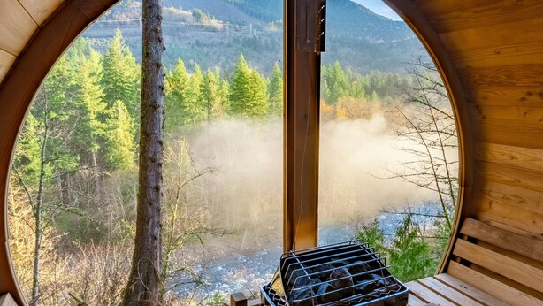 Una habitación circular de madera con vistas a un bosque y montañas.
