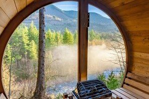 Een ronde kamer met houten wanden en uitzicht op een bos en bergen.
