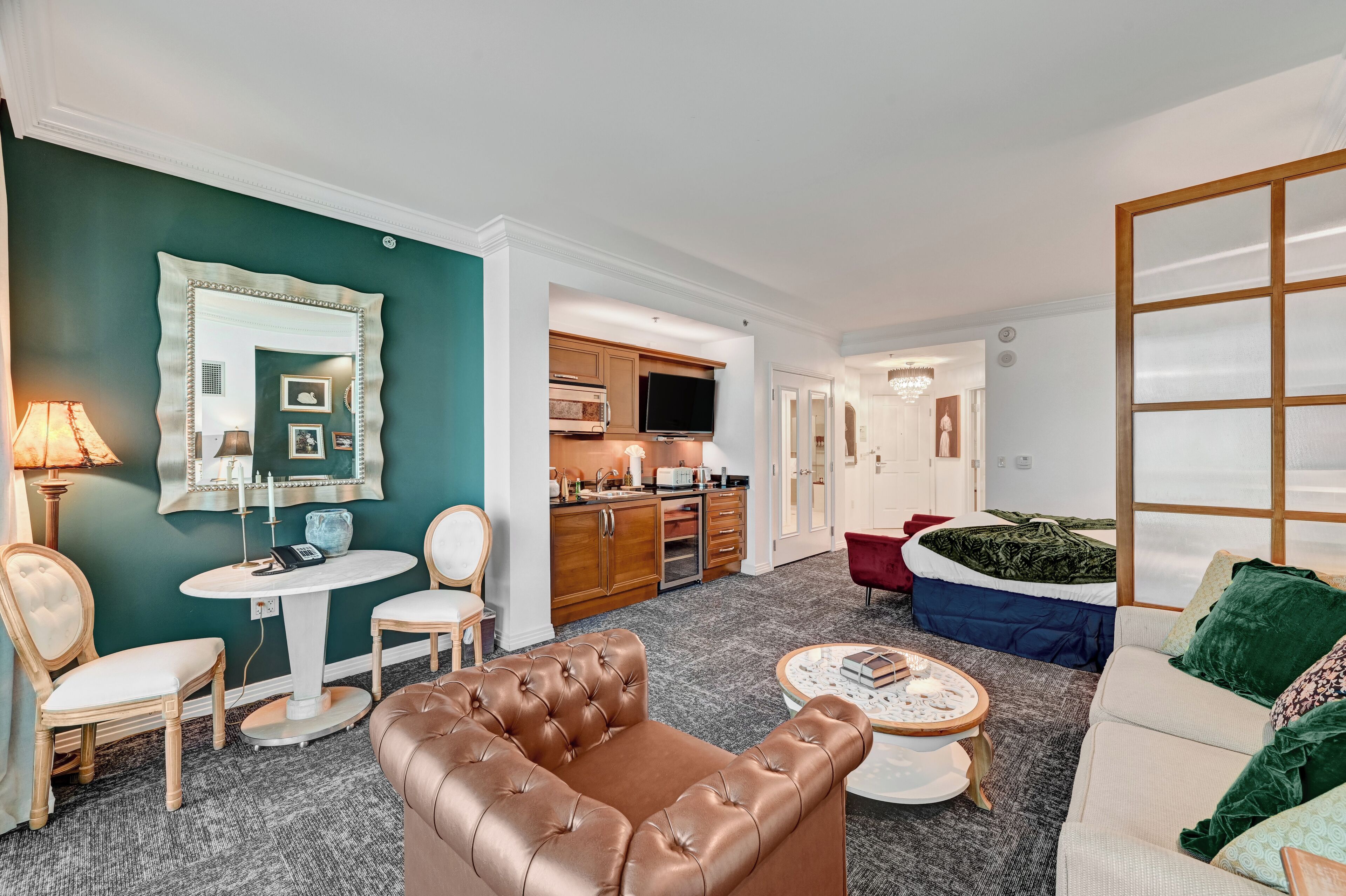 A living room with a brown leather sofa, a round coffee table, and a teal accent wall.