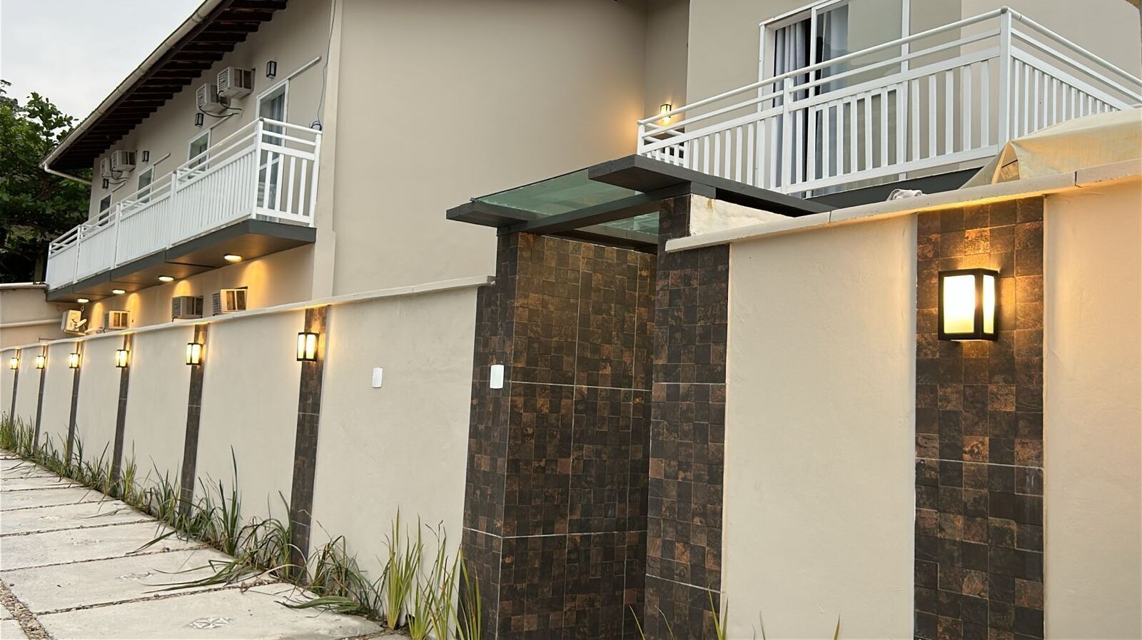 A modern building with a balcony, stone wall, and outdoor lighting.