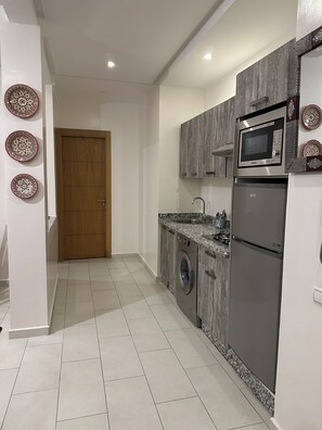 Frigorífic, microones, cafetera i tetera i una taula de menjador