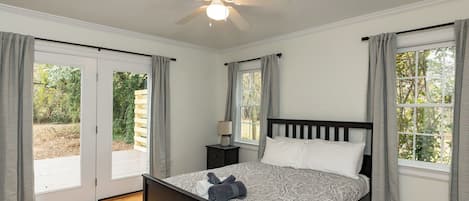 A bedroom with a bed, a ceiling fan, a nightstand, and a window with curtains.