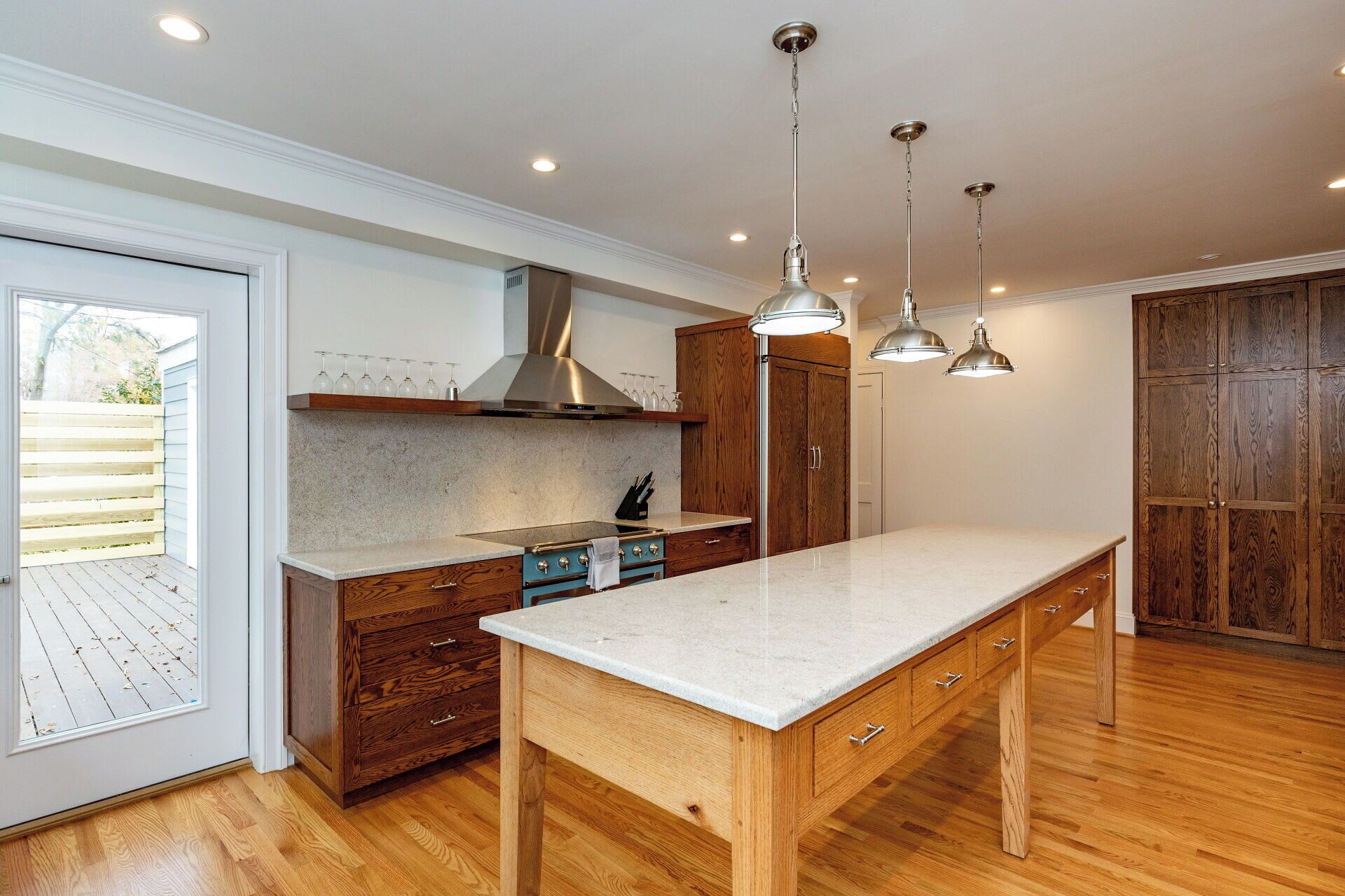 A modern kitchen with wooden cabinets, a marble countertop, and pendant lighting.