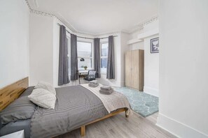 Un dormitorio con cama, escritorio y armario.
