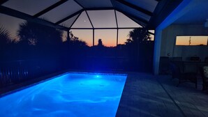 Een zwembad met glazen dak, omringd door een terras met stoelen en een tafel.