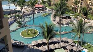 Un complexe hôtelier doté d’une piscine centrale, de palmiers et offrant une vue sur la mer.