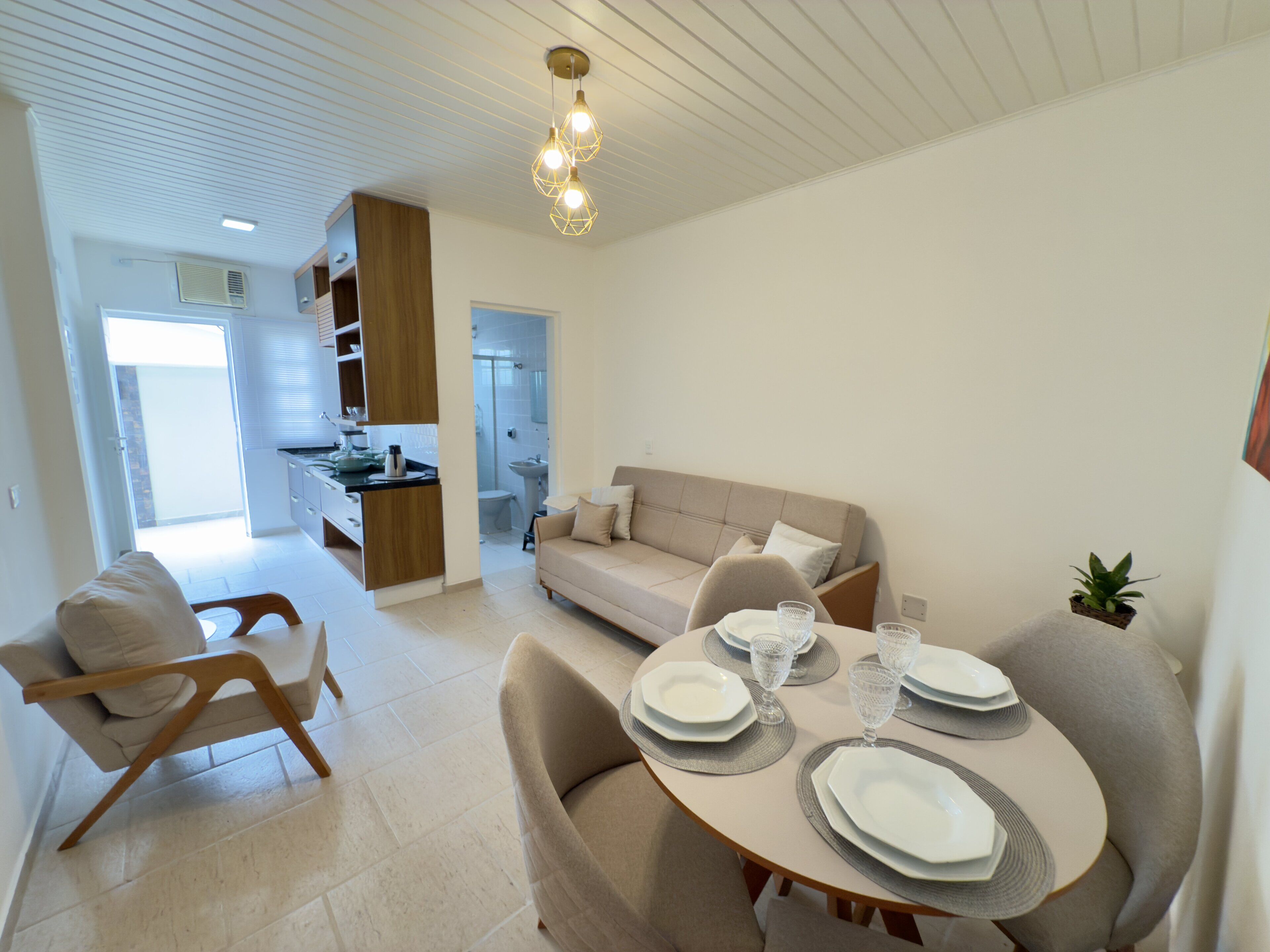 A modern living room with a dining area, a sofa, and a kitchen in the background.