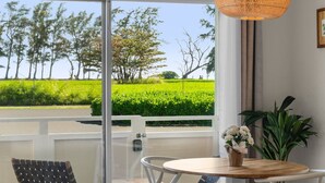 Ein Balkon mit Blick auf ein grünes Feld und Bäume, ein Tisch mit einem Blumenstrauß und einer hängenden Leuchte.