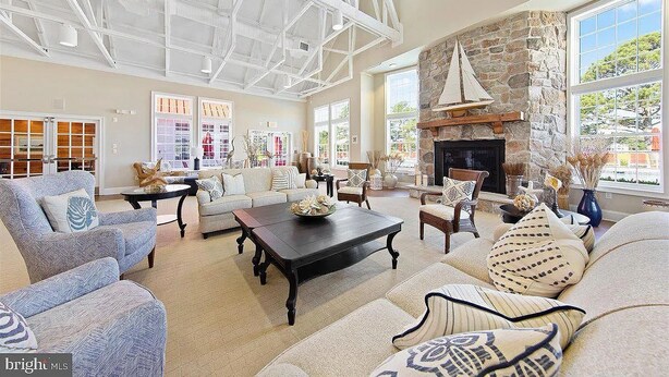 A spacious living room with a high ceiling, large windows, a stone fireplace, and comfortable seating. - Spacious Resort Villa Near Beach - VBBL (Ocean View)
