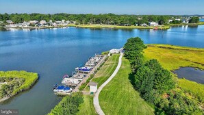 A lakeside property with a dock, grassy areas, and a pathway leading to a building. - Spacious Resort Villa Near Beach - VBBL (Ocean View)