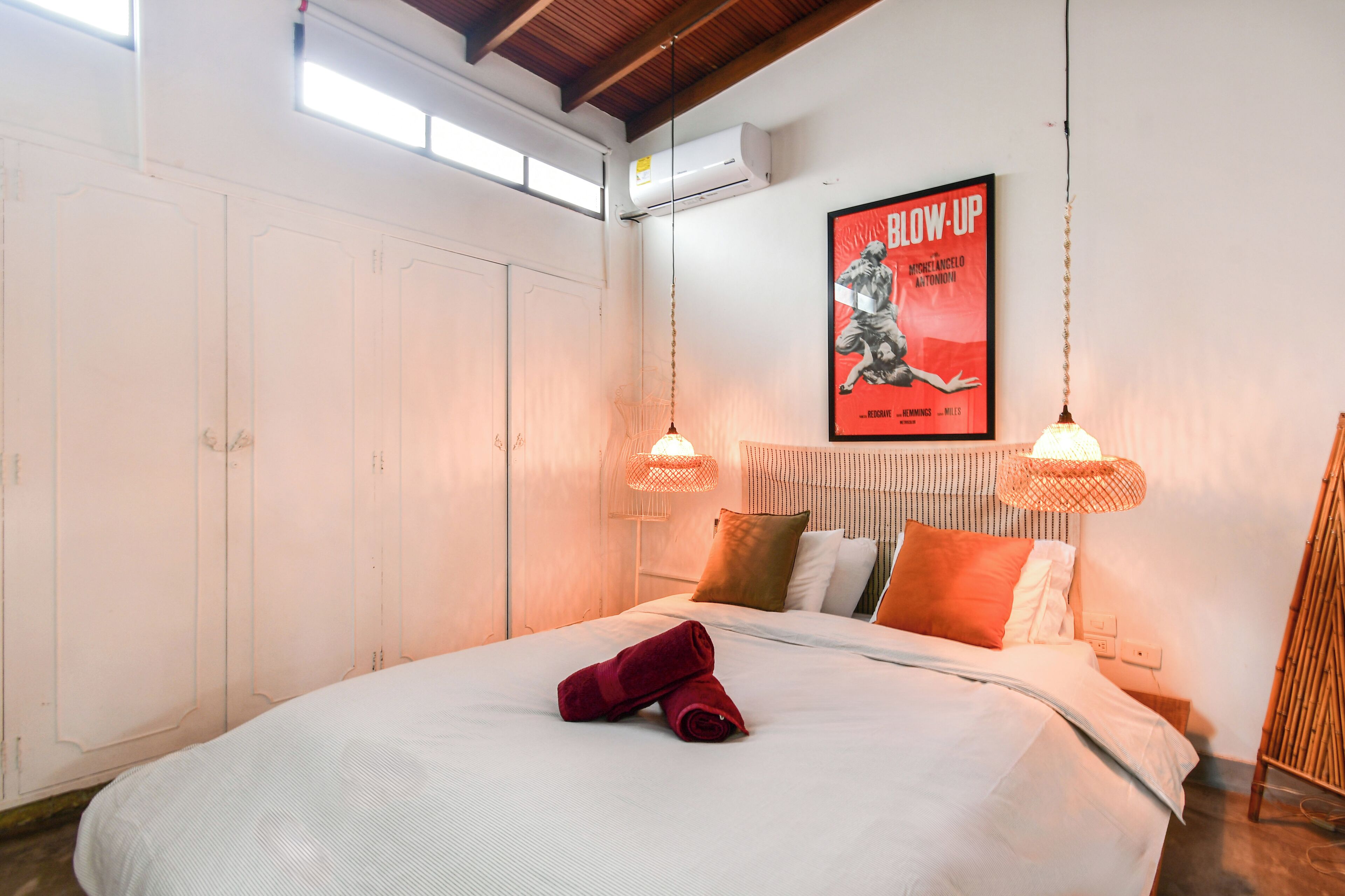 Un dormitorio con una cama grande, paredes blancas y un cartel en la pared.