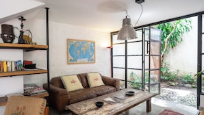 A cozy living room with a brown leather sofa, a wooden coffee table, and a bookshelf. - Casa Bolivar by Wynwood House (Medellín)