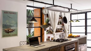 A modern kitchen with a central island, bar stools, a laptop, and a large window with curtains. - Casa Bolivar by Wynwood House (Medellín)